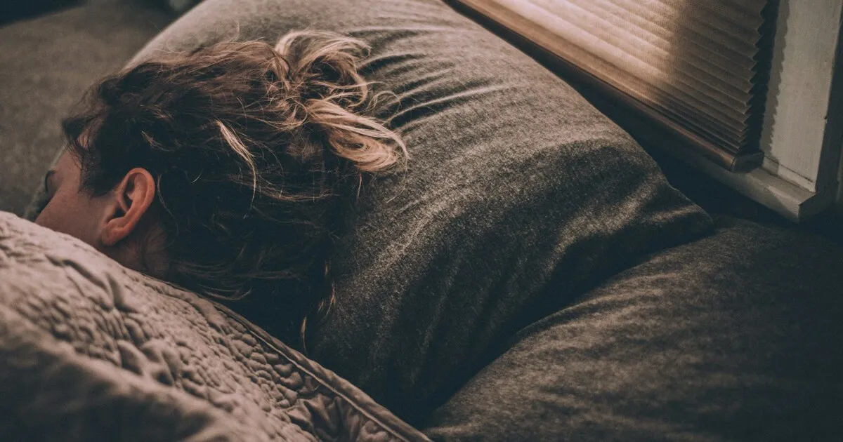 Person asleep in bed with the face turned into the pillow